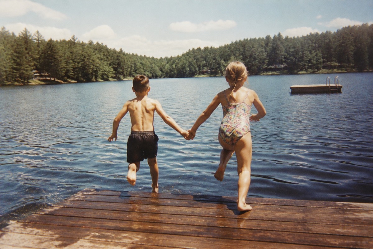 Two children jumping into a lake